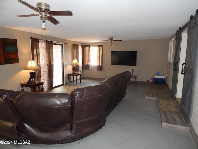 living room featuring a barn door, ceiling fan, and concrete floors