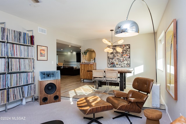 living area featuring light wood-type flooring and a notable chandelier