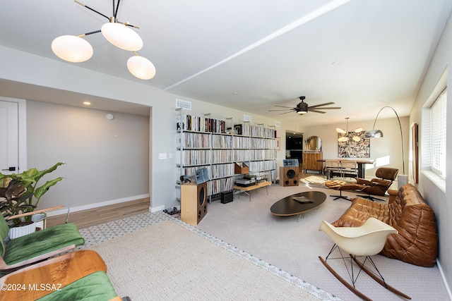 living room featuring ceiling fan with notable chandelier and light wood-type flooring