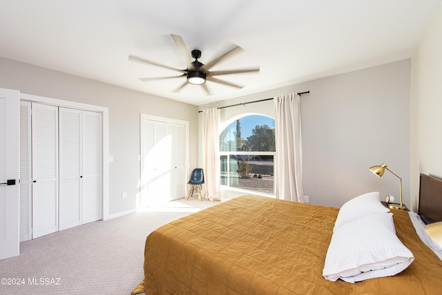 bedroom with carpet, ceiling fan, and two closets