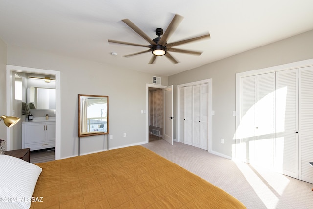 unfurnished bedroom featuring multiple closets, ceiling fan, carpet floors, and ensuite bath