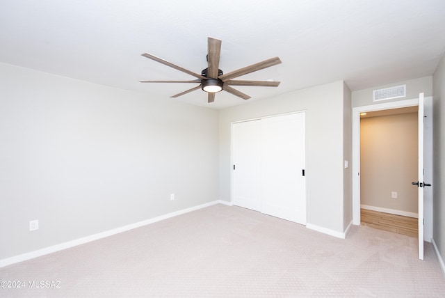 unfurnished bedroom with ceiling fan, light colored carpet, and a closet