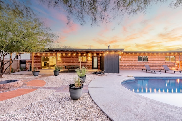 pool at dusk with a patio area