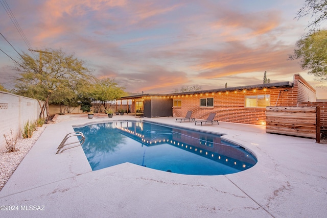 pool at dusk featuring a patio