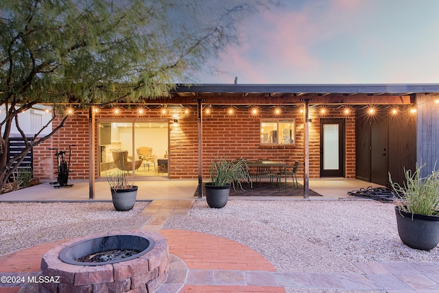 back house at dusk with a patio and an outdoor fire pit