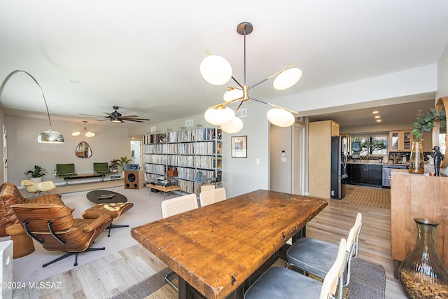 dining space with ceiling fan with notable chandelier and light wood-type flooring