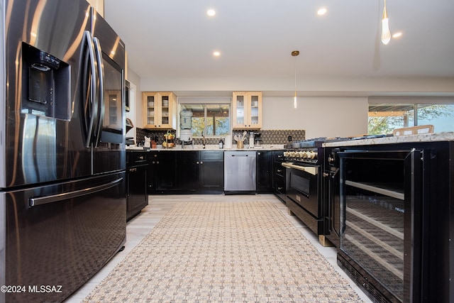 kitchen with decorative backsplash, black fridge, hanging light fixtures, and dishwasher