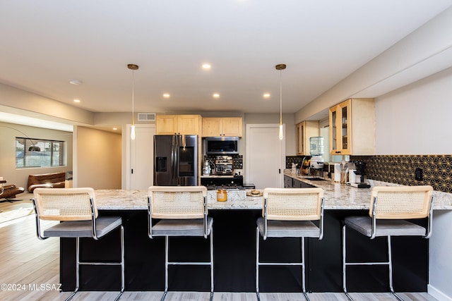 kitchen featuring a breakfast bar, pendant lighting, stainless steel appliances, and light wood-type flooring