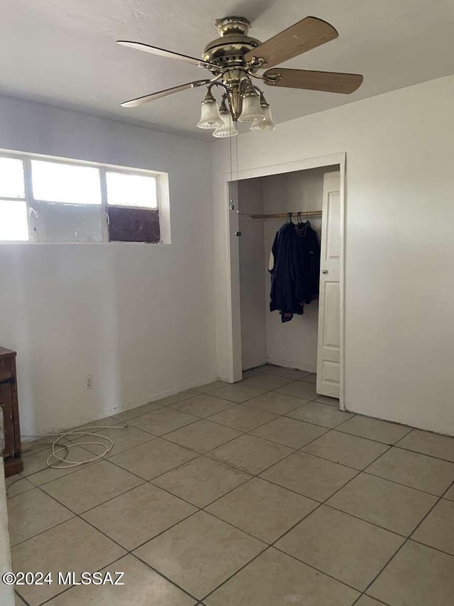 unfurnished bedroom featuring ceiling fan, light tile patterned flooring, and a closet