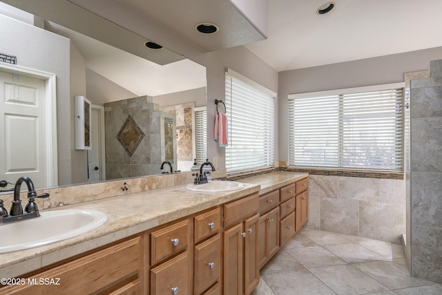 bathroom featuring tile patterned floors, vanity, lofted ceiling, and tiled shower