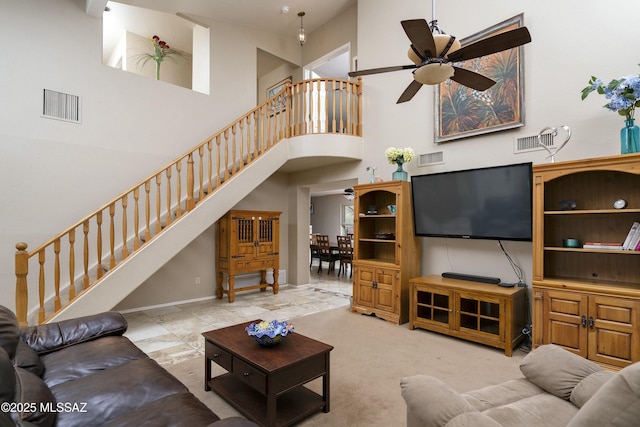 carpeted living room featuring a towering ceiling and ceiling fan