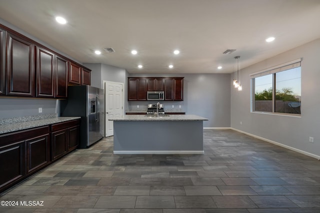 kitchen featuring appliances with stainless steel finishes, light stone counters, pendant lighting, and sink