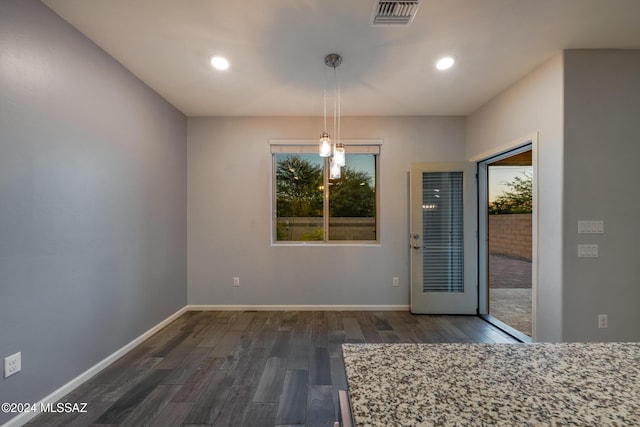 unfurnished dining area featuring dark wood-type flooring and a wealth of natural light