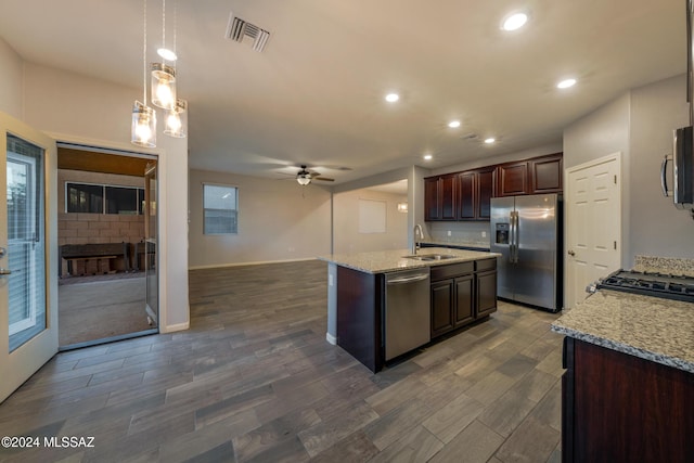 kitchen featuring pendant lighting, a center island with sink, sink, ceiling fan, and appliances with stainless steel finishes