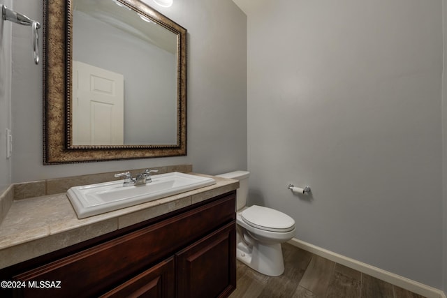 bathroom with hardwood / wood-style floors, vanity, and toilet