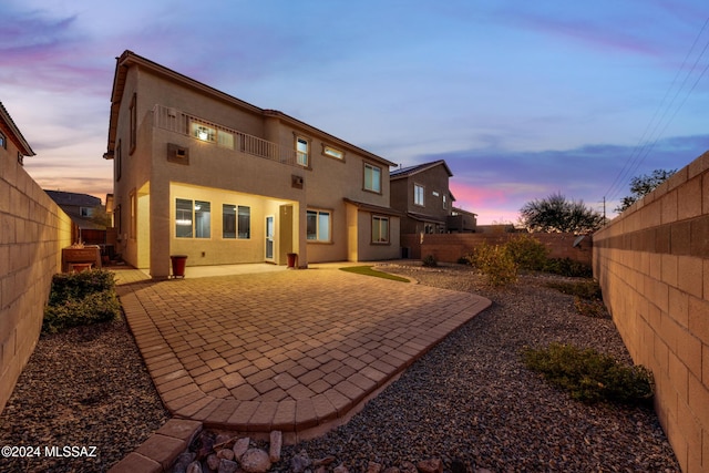 back house at dusk with a patio