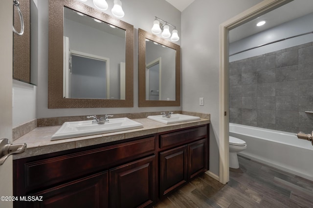 full bathroom with tiled shower / bath combo, toilet, wood-type flooring, and vanity