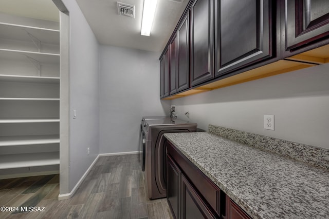 laundry area with cabinets, washer and clothes dryer, and dark wood-type flooring