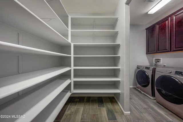 laundry area featuring cabinets, wood-type flooring, and independent washer and dryer