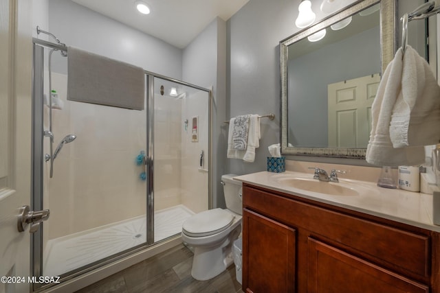 bathroom featuring toilet, vanity, wood-type flooring, and walk in shower