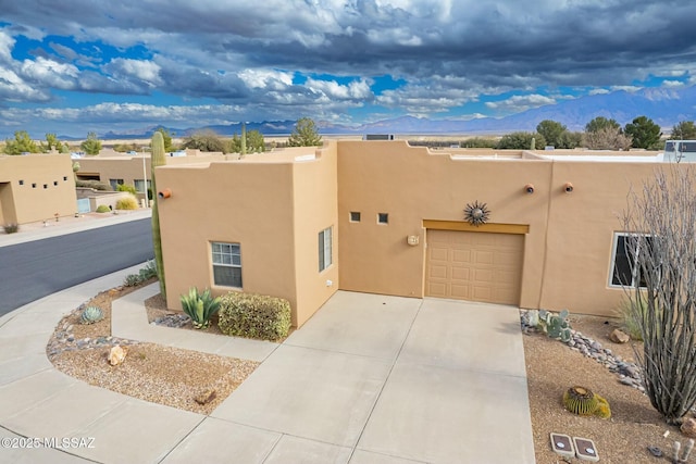 pueblo-style home with a garage and a mountain view