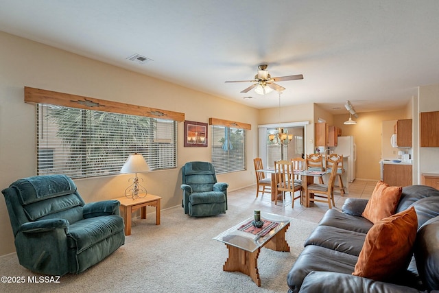 living room featuring plenty of natural light, ceiling fan with notable chandelier, and light tile patterned floors