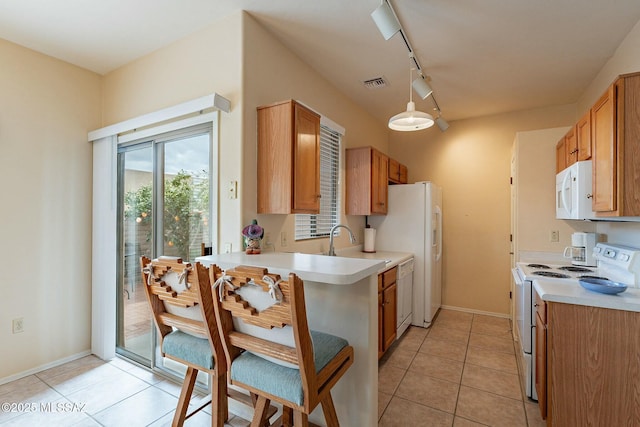 kitchen featuring sink, white appliances, hanging light fixtures, track lighting, and light tile patterned flooring