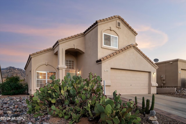 mediterranean / spanish-style home featuring driveway, a tiled roof, and stucco siding