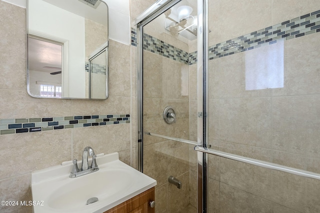 bathroom with vanity, walk in shower, and tile walls