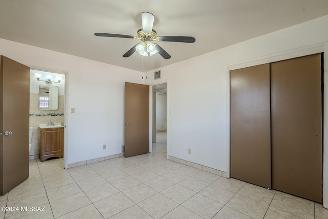 unfurnished bedroom with ceiling fan, sink, connected bathroom, a closet, and light tile patterned flooring