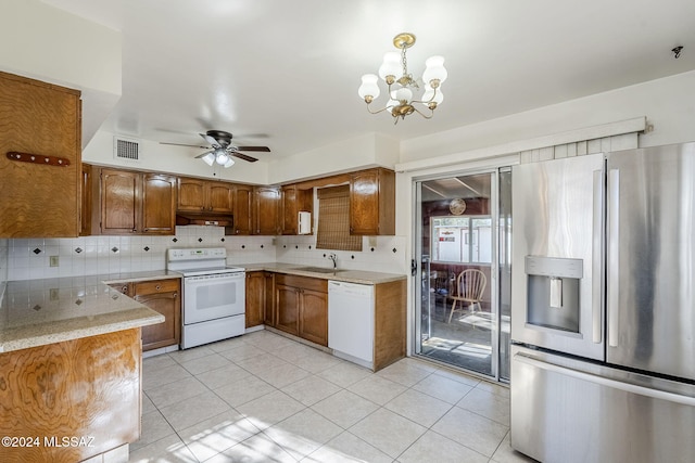 kitchen featuring sink, backsplash, decorative light fixtures, white appliances, and ceiling fan with notable chandelier