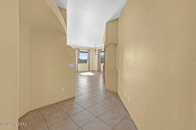 hallway featuring light tile patterned floors and an inviting chandelier