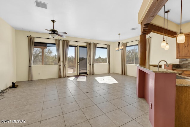 kitchen with plenty of natural light, beamed ceiling, hanging light fixtures, and ceiling fan with notable chandelier