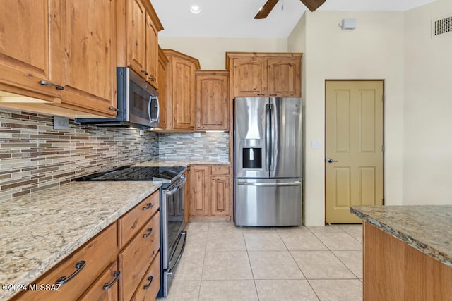 kitchen featuring backsplash, light stone counters, light tile patterned floors, and stainless steel appliances