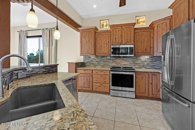 kitchen with backsplash, light stone counters, stainless steel appliances, sink, and pendant lighting