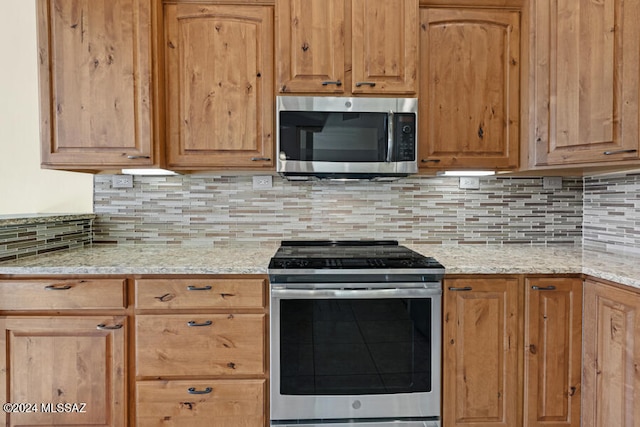 kitchen featuring decorative backsplash, light stone counters, and appliances with stainless steel finishes