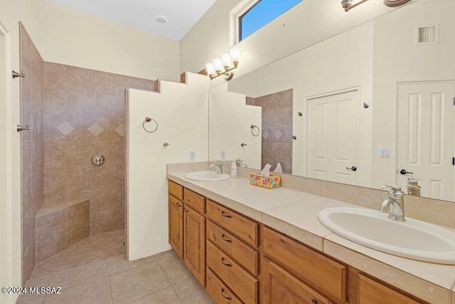 bathroom featuring a tile shower, tile patterned flooring, and vanity