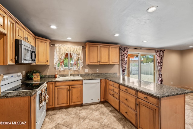 kitchen featuring kitchen peninsula, light tile patterned floors, white appliances, and sink