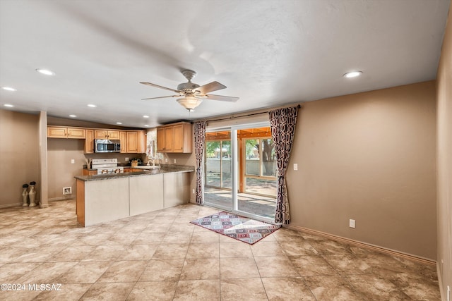 kitchen featuring ceiling fan, sink, white range oven, kitchen peninsula, and dark stone counters