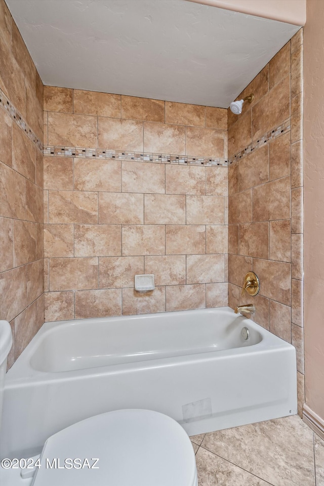 bathroom with tile patterned floors, tiled shower / bath combo, and toilet