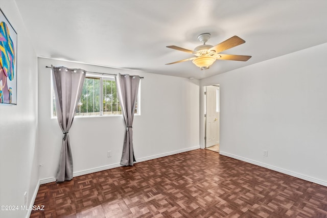 unfurnished room with ceiling fan and dark parquet floors