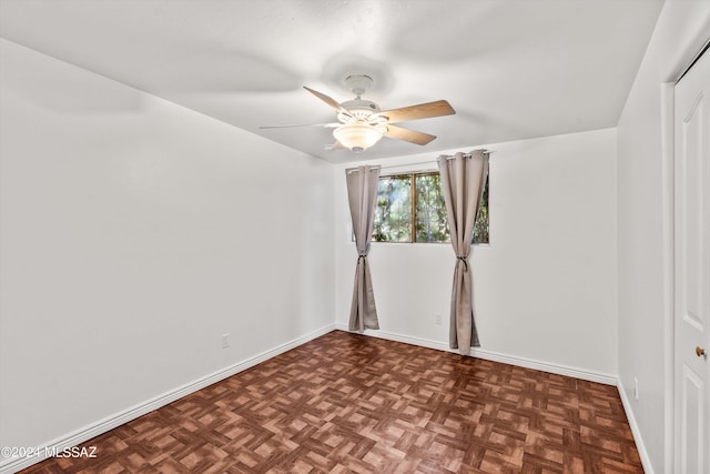 spare room featuring dark parquet flooring and ceiling fan