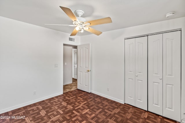 unfurnished bedroom featuring dark parquet flooring, a closet, and ceiling fan