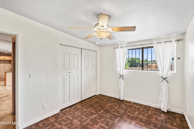 unfurnished bedroom featuring dark parquet floors, a closet, ceiling fan, and lofted ceiling