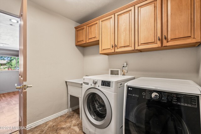 clothes washing area with cabinets, washing machine and dryer, and tile patterned flooring