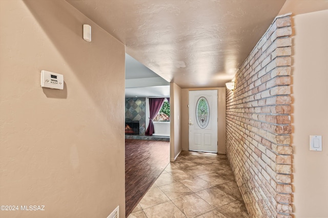 entrance foyer with a large fireplace, brick wall, and light hardwood / wood-style flooring