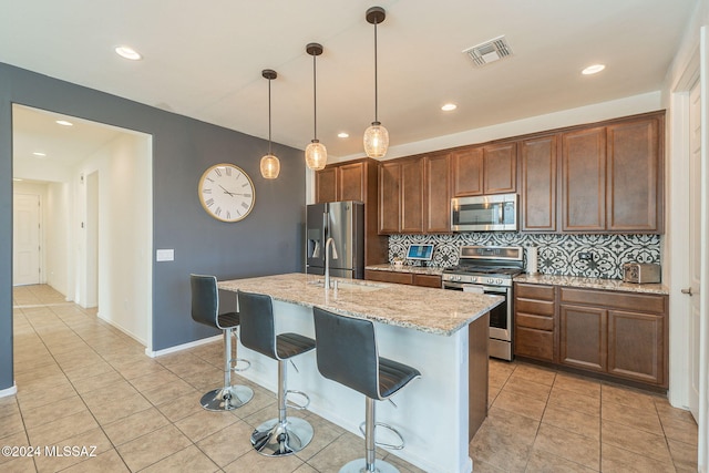 6551 E Via Arroyo Largo, Tucson, AZ 85756 - kitchen with stainless steel appliances, a sink, backsplash, an island with sink, and a breakfast bar