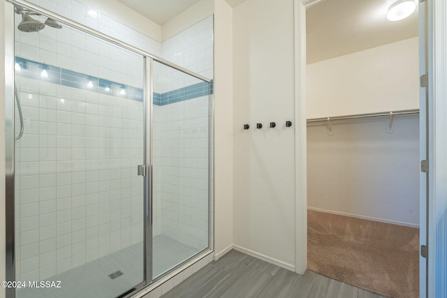 6551 E Via Arroyo Largo, Tucson, AZ 85756 - full bathroom featuring a shower stall, a walk in closet, baseboards, and wood finished floors