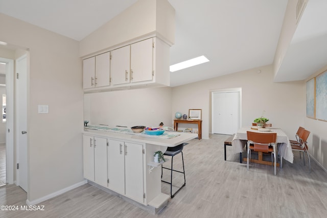 kitchen with light hardwood / wood-style floors, white cabinetry, and vaulted ceiling