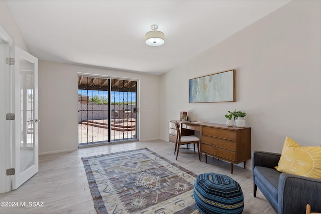 home office with light hardwood / wood-style floors and vaulted ceiling